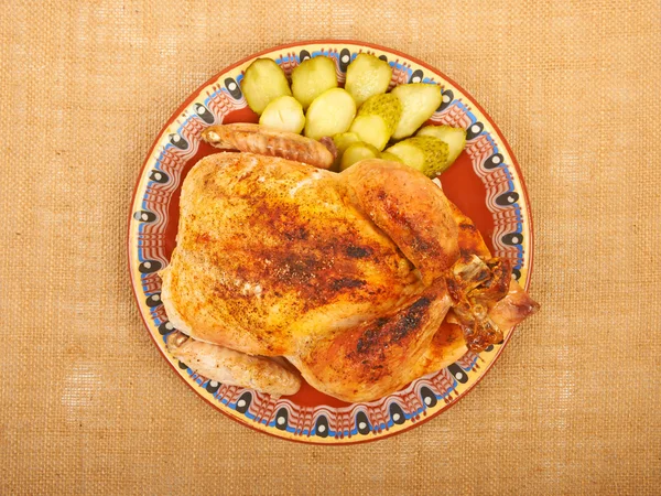 Жареная курица на тарелке с огурцами на холсте . — стоковое фото