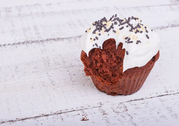 Cupcake au chocolat avec crème otkusanny sur bois blanc — Photo