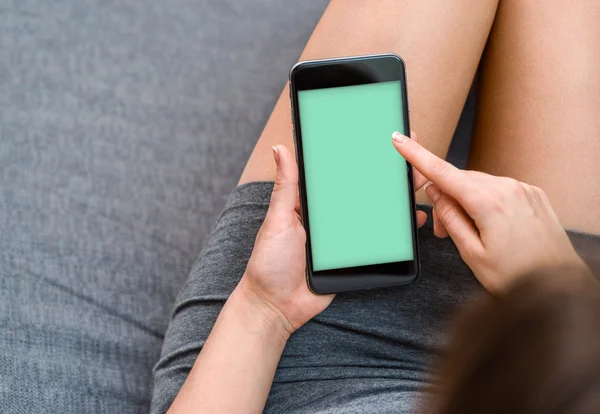 La mujer descansa con el smartphone en el sofá . — Foto de Stock