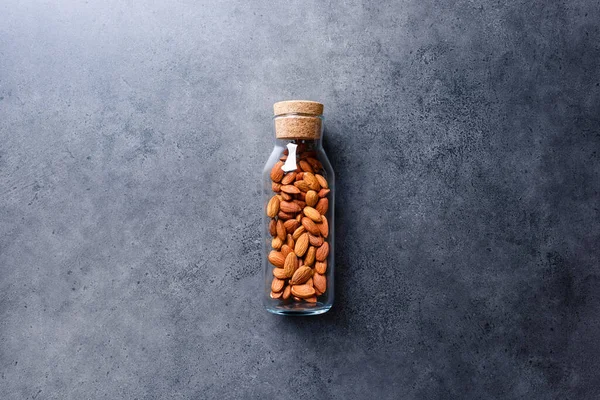 Almond nuts in corked glass jar on a concrete desktop — Stock Photo, Image