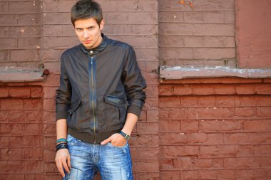 Tuğla duvarın yanında ceketli adamı