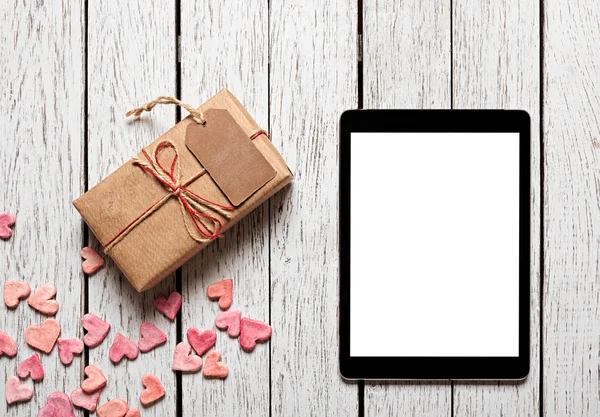 Gift box with gift tag, hearts and tablet computer — Stock Photo, Image