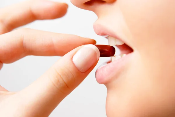 Woman taking dark red pill — Stock Photo, Image