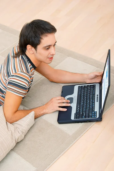 Мужчина лежит на полу с ноутбуком — стоковое фото