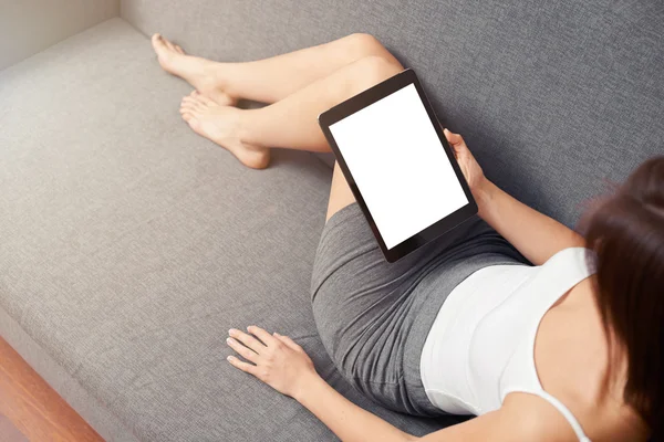 Frau ruht sich mit Tablet auf Sofa aus — Stockfoto