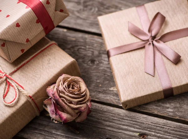Розовый цветок среди подарочных коробок — стоковое фото