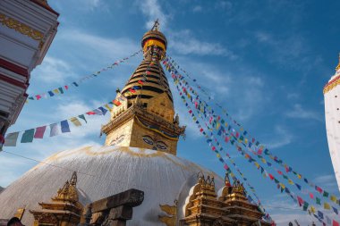 Kathmandu 'daki maymun tapınağının (Swayambhunath Tapınağı) stupası, mavi gökyüzü, rüzgarda dalgalanan dua bayraklarıyla