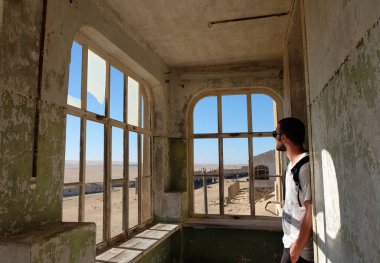 Tourist visiting the interior of one of the ruined house in the ghost town of Kolmanskop, Namibia