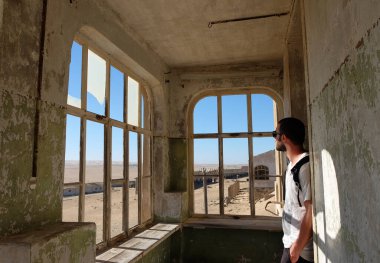 Tourist visiting the interior of one of the ruined house in the ghost town of Kolmanskop, Namibia clipart