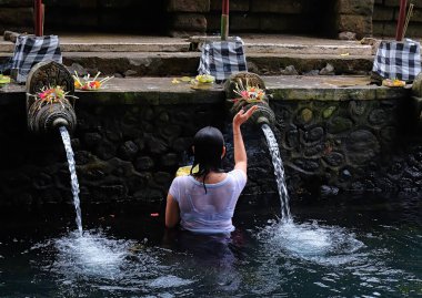 Tanınmayan bir kadın Pura Tirta Boş Tapınağı 'ndaki kutsal kaynak suyunda dua ediyor ve arındırma ayini yapıyor..