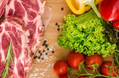 Sebzeli çiğ et ve ahşap arka planda baharatlar.