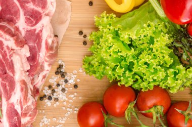 Sebzeli çiğ et ve ahşap arka planda baharatlar.