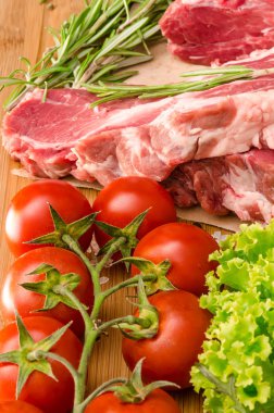 Sebzeli çiğ et ve ahşap arka planda baharatlar.