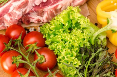 Sebzeli çiğ et ve ahşap arka planda baharatlar.