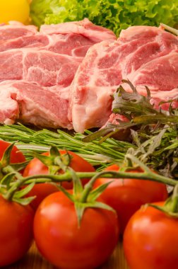 Sebzeli çiğ et ve ahşap arka planda baharatlar.