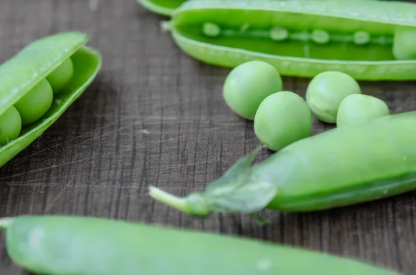 Green organic peas on wooden background, shalow focus — Stock fotografie