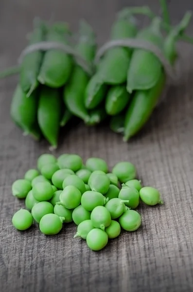 Green organic peas on wooden background, shalow focus — Stock fotografie