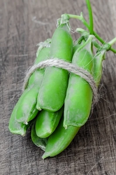 Green organic peas on wooden background, shalow focus — Stockfoto