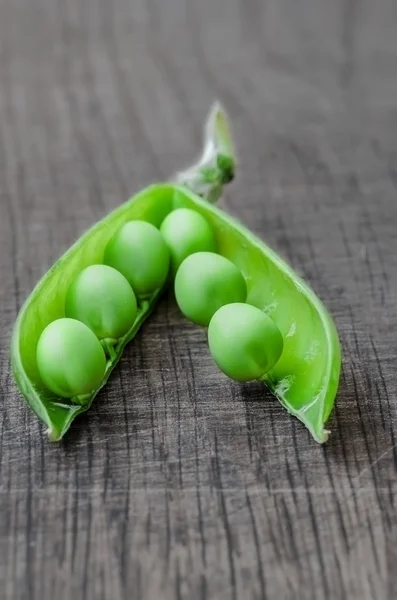 Green organic peas on wooden background, shalow focus — Stock fotografie