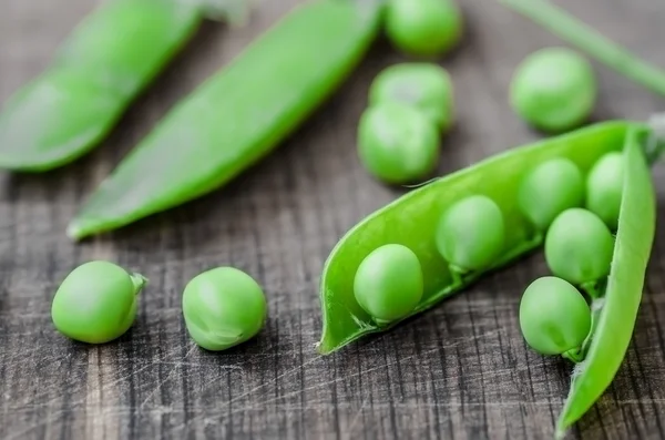 Green organic peas on wooden background, shalow focus — Stockfoto