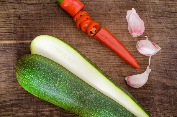 Zucchini with hot pepper and garlic on wooden table — Stock Photo, Image