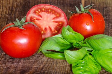 Ahşap masa üzerinde yeşil şeylerle sulu domates