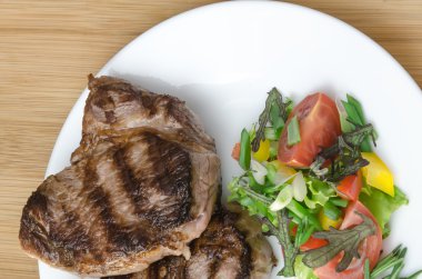 Ahşap arka plan üzerinde beyaz plaka salata ızgara et