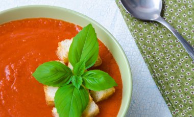 Traditional Spanish cold tomato soup gazpacho with basil and croutons on wooden table