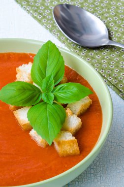 Traditional Spanish cold tomato soup gazpacho with basil and croutons on wooden table