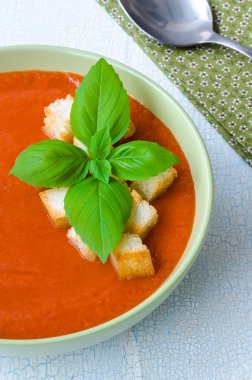 Traditional Spanish cold tomato soup gazpacho with basil and croutons on wooden table
