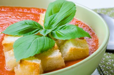 Traditional Spanish cold tomato soup gazpacho with basil and croutons on wooden table