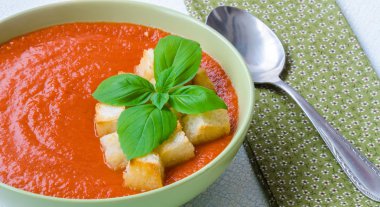 Traditional Spanish cold tomato soup gazpacho with basil and croutons on wooden table