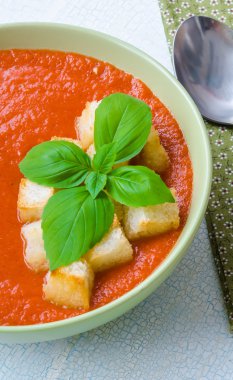 Traditional Spanish cold tomato soup gazpacho with basil and croutons on wooden table