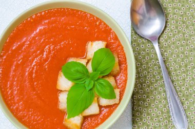Traditional Spanish cold tomato soup gazpacho with basil and croutons on wooden table