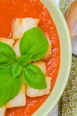 Traditional Spanish cold tomato soup gazpacho with basil and croutons on wooden table