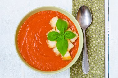 Traditional Spanish cold tomato soup gazpacho with basil and croutons on wooden table