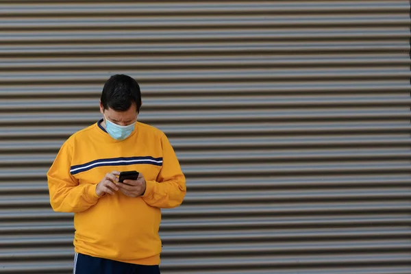 Man with face mask using smart phone on gray background. Concept pandemic virus