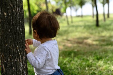 Sırtı bir ağacın gövdesine dönük küçük bir kız. Kopyalama alanı olan ağaçlar