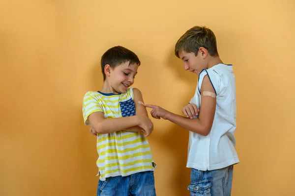 两个孩子在胳膊上戴着疫苗绷带玩得很开心 免版税图库图片