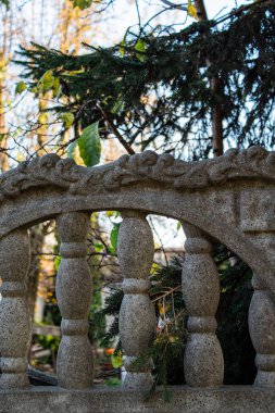 Sonbahar dallarının arka planında şekilli sütunlarla süslenmiş taş bir çit.