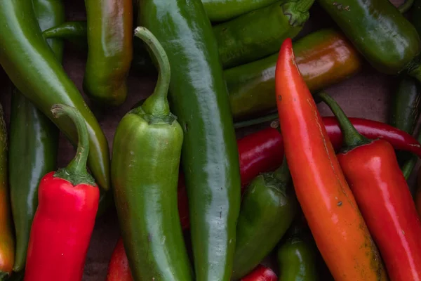 Lots of large hot red and green peppers close up in daylight — Stock Photo, Image