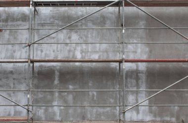 Binanın dış cephesinde gri bir inşaat alanında metal bir yapı var.