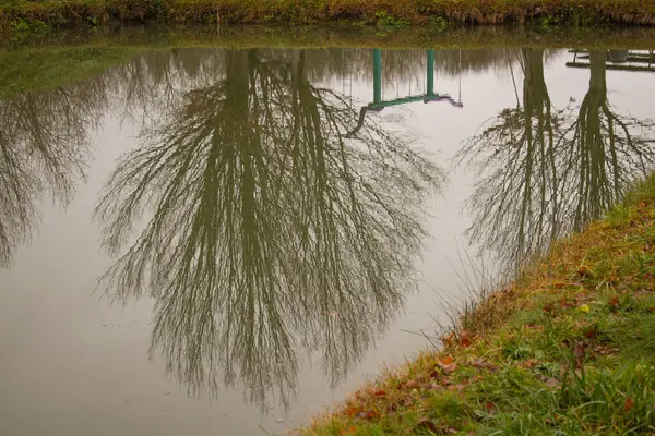 Reflexion der Baumkronen und Schaukeln auf der Wasseroberfläche des Teiches — Stockfoto