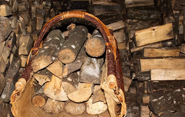 Hermosa cesta de mimbre llena de leña contra el fondo de la leña —  Fotos de Stock