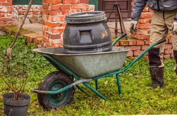 Ein Mann in Arbeitsuniform in der Nähe eines Wasserfasses in einem Einkaufswagen — Stockfoto