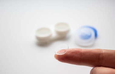 Beyaz konteynırın arka planında parmak üzerinde şeffaf lens 