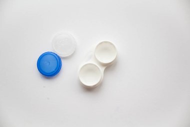 Beyaz arka planda kapaklar uzanmak üzere lensler için açık beyaz bir kap 