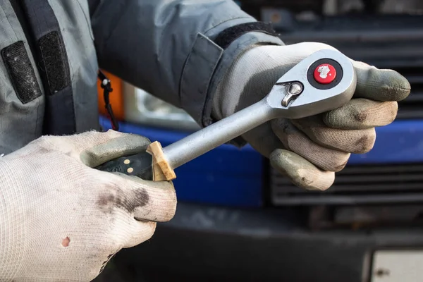 A man wearing work gloves holds athe key for ratchet heads in his hand — Stock Photo, Image