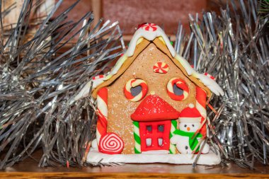Oyuncak zencefilli kurabiye evi şöminenin üstünde gümüş bir çelengin yanında bir kardan adam 