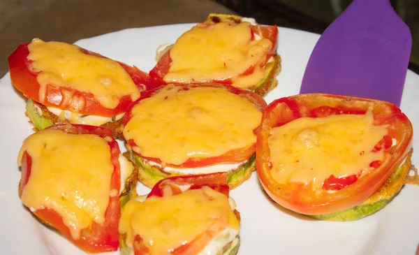 Βάζοντας μια σπάτουλα σε ένα πιάτο ψητά κολοκυθάκια με ντομάτες και τυρί — Φωτογραφία Αρχείου